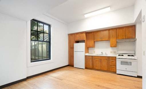 a kitchen with white appliances and wooden cabinets and a large window