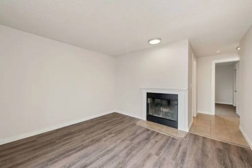 A room with a fireplace and wooden flooring.
