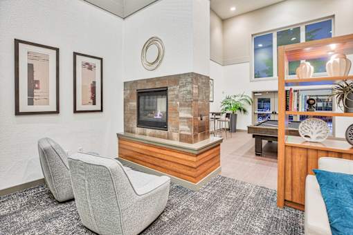 A living room with a grey carpet and a stone fireplace.