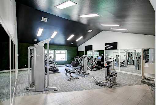 A gym with a variety of equipment including treadmills, weights, and exercise machines.