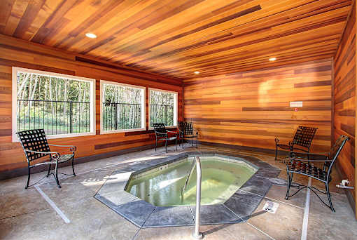 A hot tub in a wooden room with chairs around it.
