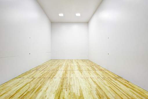 A squash court with wooden flooring and white walls.