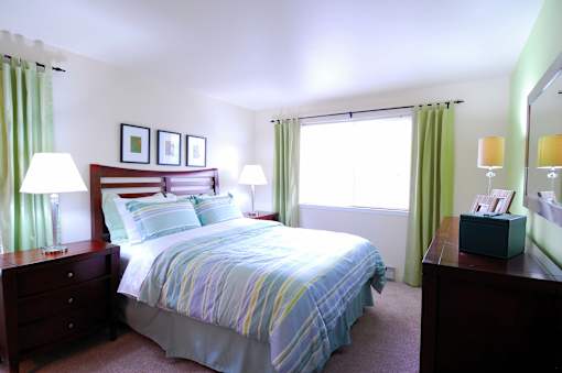 A bedroom with a bed, nightstands, and a window with green curtains.