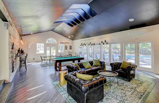 A living room with a black couch and a blue rug.