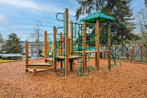 A playground with a green canopy and a wooden swing set.