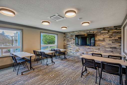 A room with tables and chairs and a stone wall.