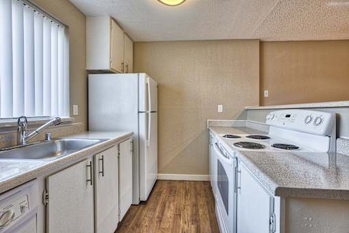 A kitchen with white appliances and wooden floors.