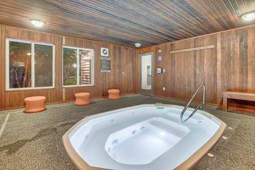 A hot tub is in the middle of a room with wood paneling.