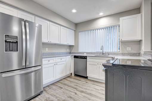 A modern kitchen with a stainless steel refrigerator and white cabinets.