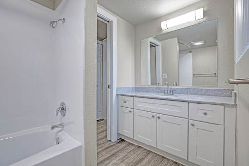 A white bathroom with a tub, sink, and mirror.