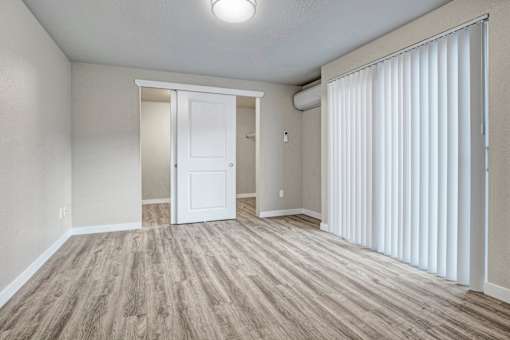 A room with a white door and a window with white blinds.