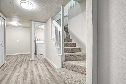 A hallway with a staircase and a white door.