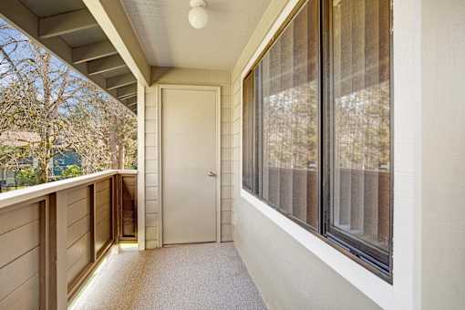 A white door is on the left side of a balcony with a carpeted floor.