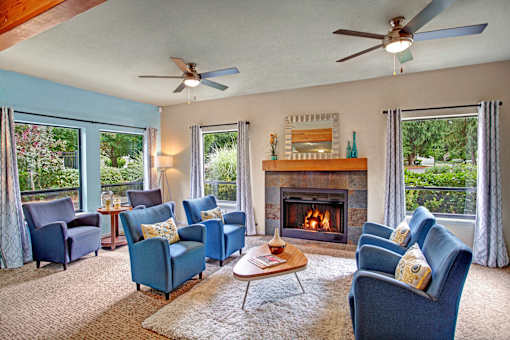 A living room with blue chairs and a fireplace.