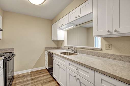 A kitchen with white cabinets and a marble countertop.