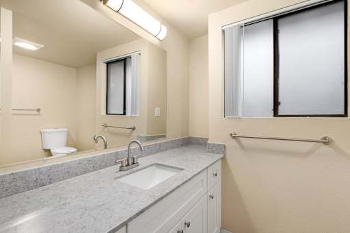 A bathroom with a sink, mirror, toilet, and shower.