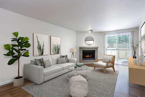 A living room with a grey couch, a fireplace, and a potted plant.
