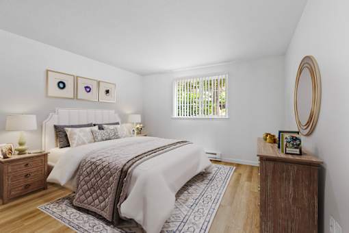 A bedroom with a large bed and a wooden nightstand.