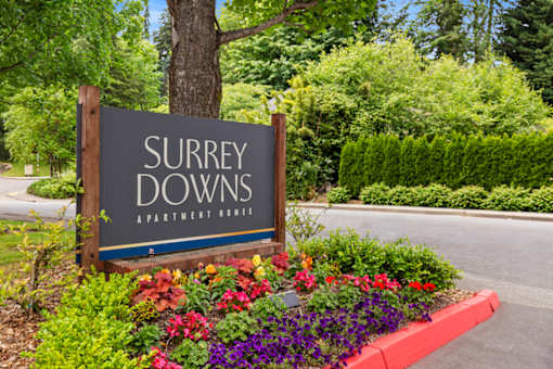 A Surrey Downs Apartment Homes sign is surrounded by flowers.