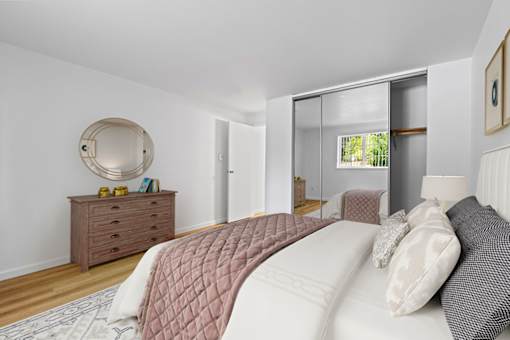 A bedroom with a large bed and a dresser with a mirror.