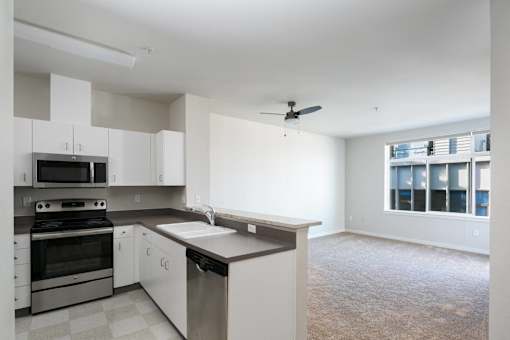 an empty kitchen with white cabinets and stainless steel appliances