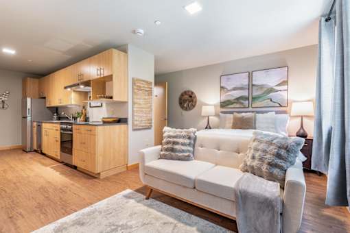 A modern living room with a white couch and a kitchen area in the background.