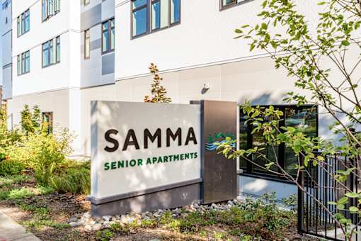 A sign for Samma Senior Apartments is in front of a building.
