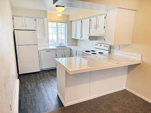 A kitchen with white appliances and cabinets.