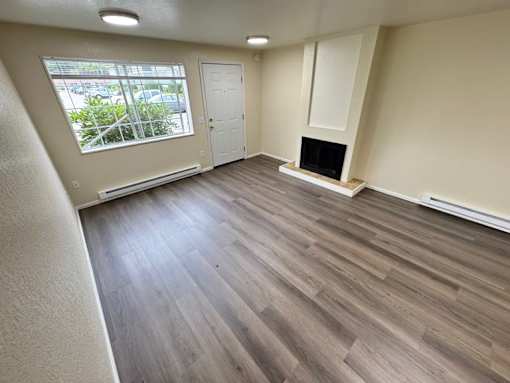 A room with a fireplace and a window overlooking a parking lot.