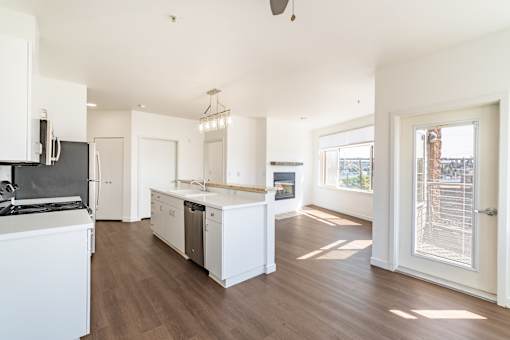 A kitchen with white appliances and wooden floors.