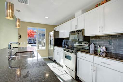 A kitchen with white cabinets and a black stove top oven.