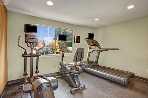 A home gym with a treadmill, elliptical trainer, and other exercise equipment.