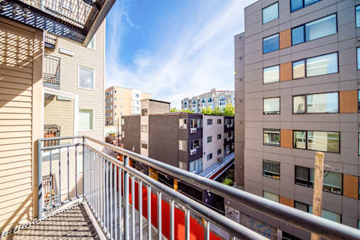 A balcony with a metal railing overlooks a cityscape.