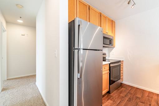 A kitchen with a stainless steel refrigerator and wooden cabinets.