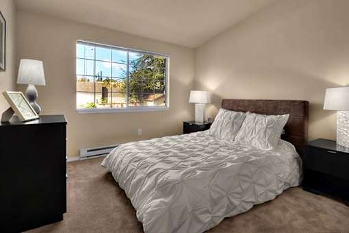 A bedroom with a large bed and two lamps.