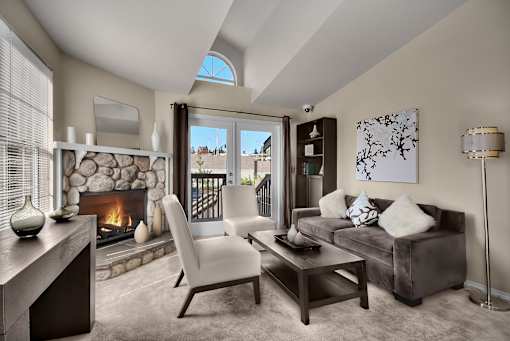 A modern living room with a stone fireplace and a skylight.
