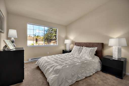 A bedroom with a large bed and two lamps.