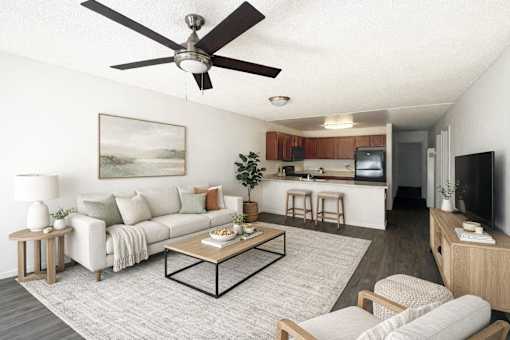 photo of living room with couches rug, table, ceiling fan and background of kitchen