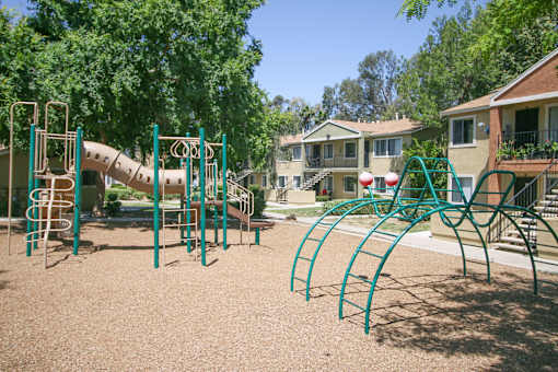 A playground with a green slide and monkey bars.