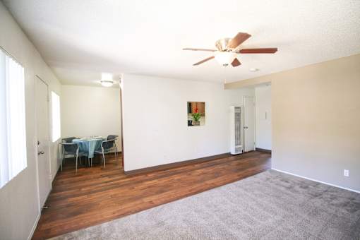 A room with a ceiling fan and a dining table with chairs.