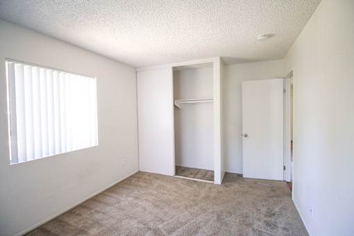 A room with a carpeted floor and a window with blinds.