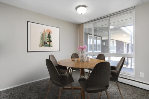 a dining area with a wooden table and chairs and a large window with a view of a