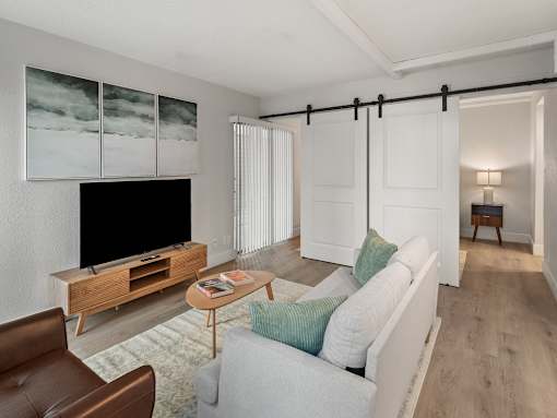 A living room with a white couch, a brown leather chair, a wooden entertainment center, and a painting on the wall.
