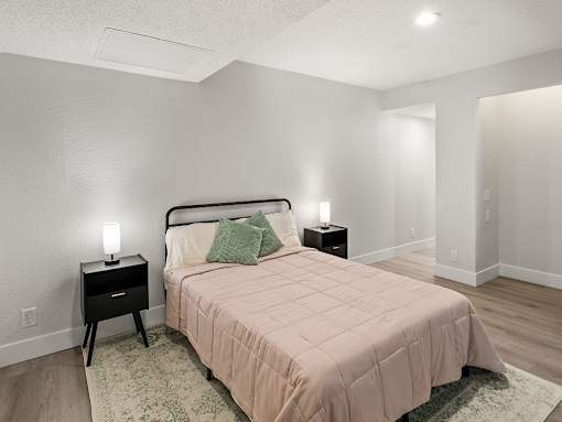A bedroom with a bed, nightstands, and a rug.