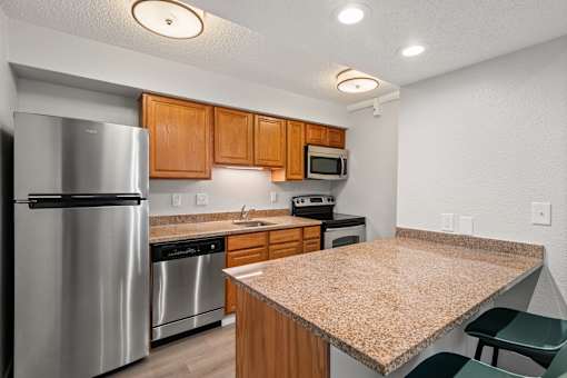 A kitchen with a granite counter top and stainless steel appliances.