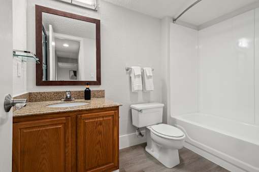 A bathroom with a toilet, sink, and mirror.