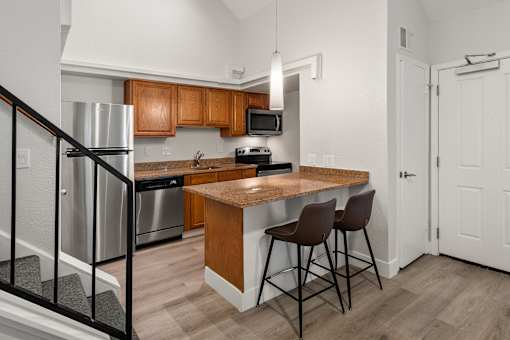 A kitchen with a refrigerator, microwave, oven, and sink.