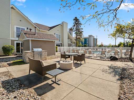 A patio with a table and chairs is surrounded by a fence and houses.