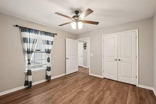 A room with a ceiling fan and wooden flooring.