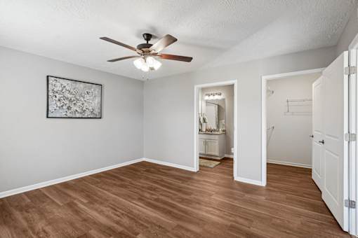 A room with a ceiling fan and a painting on the wall.